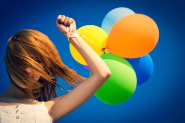 Kızıl saçlı kız mavi gökyüzü arka plan, renk balonlar ile.