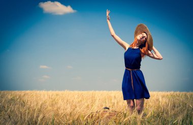 Redhead girl in blue dress and hat at spring wheat field. clipart