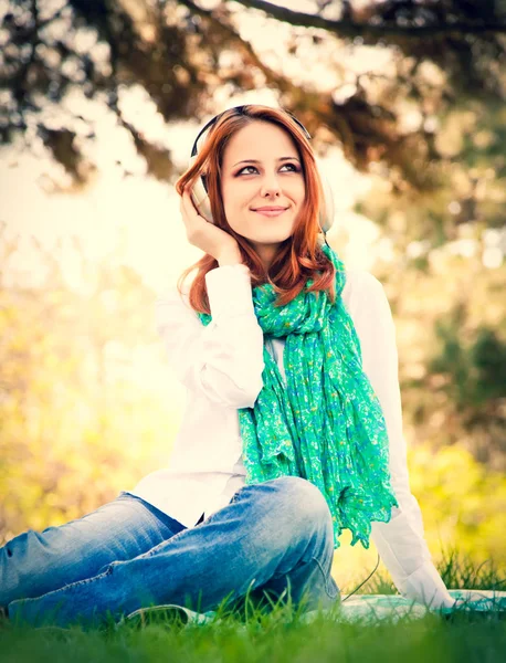 Redhead Dziewczyna Słuchawek Siedząc Trawie Parku — Zdjęcie stockowe