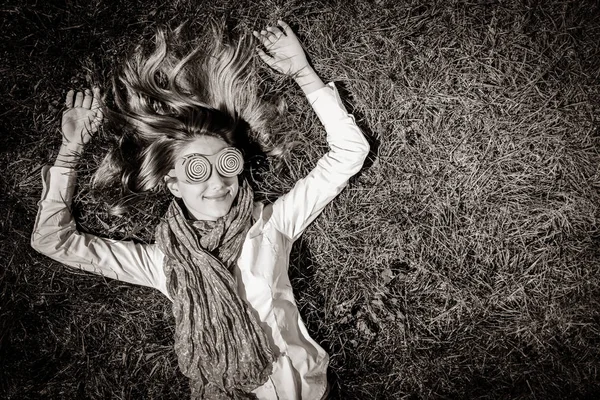 草の上に横たわるおかしい眼鏡の少女 黒と白のスタイルのイメージ — ストック写真