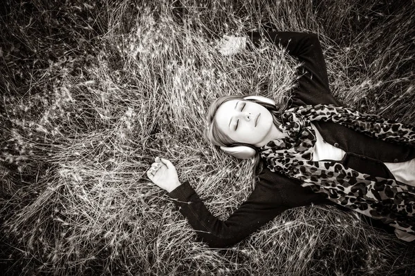 若いファッションを浮かべて草原に横たわってヘッドフォン 黒と白の色のイメージ — ストック写真