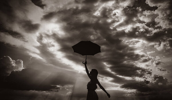 Photo of young beautiful woman with red umbrella on the sky background. Image in black and white color style