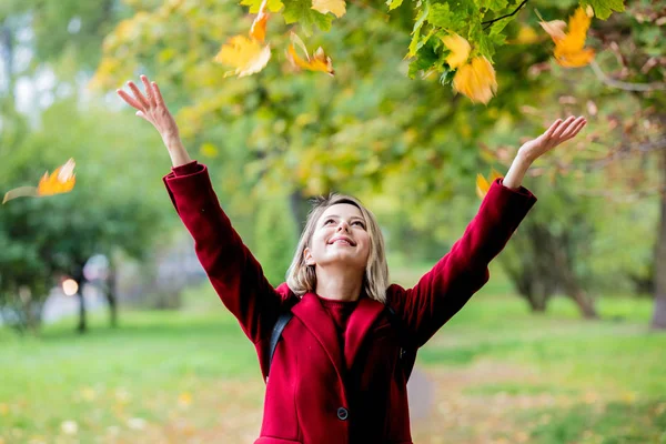 若いスタイルは 秋の公園の路地で葉を持つ少女 — ストック写真