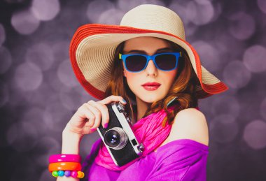Bokeh arka plan üzerinde kamera ile şapkalı komik Kızıl saçlı kız