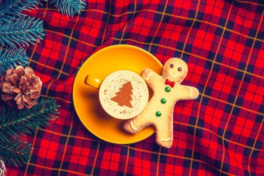 sarı fincan Cappuccino krem Noel ağacı ve tartan zemin üzerine zencefilli kurabiye adam ve çam dalı