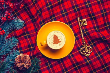 sarı fincan Cappuccino krem Noel ağacı ve çam Şubesi anahtarla tartan zemin üzerine