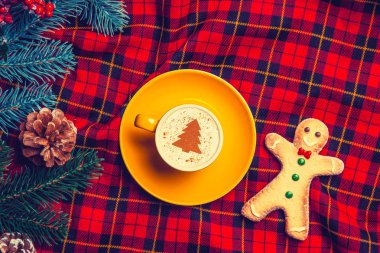 sarı fincan Cappuccino krem Noel ağacı ve tartan zemin üzerine zencefilli kurabiye adam ve çam dalı