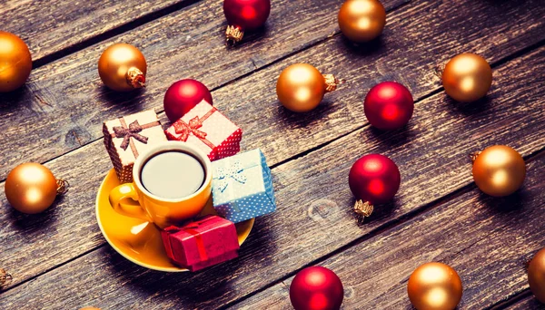 Gelbe Tasse Mit Christbaumkugeln Und Geschenk Auf Holztisch — Stockfoto