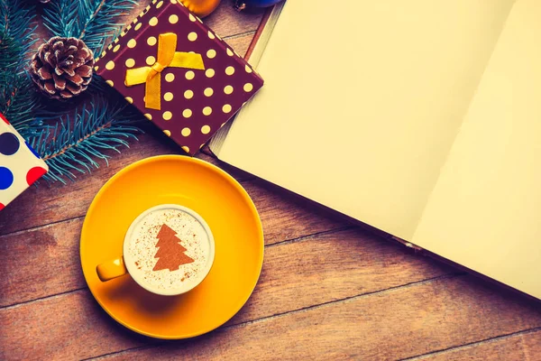黄色杯卡布奇诺与奶油圣诞树和打开书在木桌附近的玩具 — 图库照片
