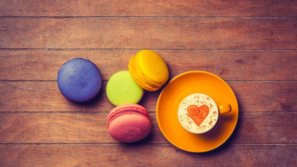Cup and macarons on wooden background — Stock Photo, Image