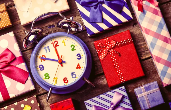 Colorful gifts and clock on the table — Stock Photo, Image