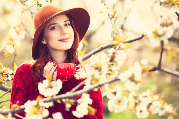 Femme en pull rouge et chapeau avec tasse — Photo