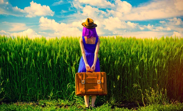 Mladá žena s kufrem v blízkosti pole — Stock fotografie