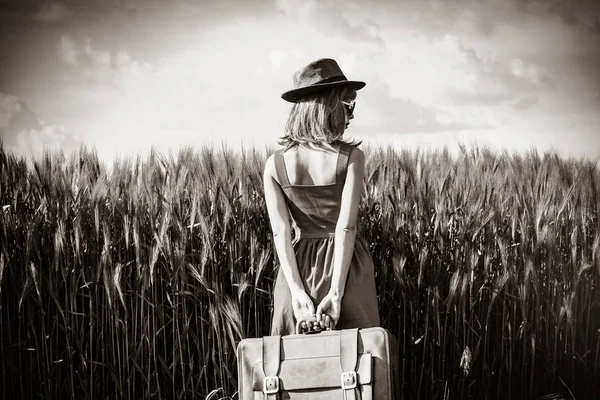 Молодая женщина с чемоданом возле поля — стоковое фото
