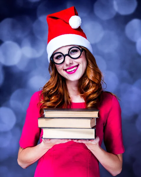 Menina ruiva em chapéu de Natal com livros — Fotografia de Stock