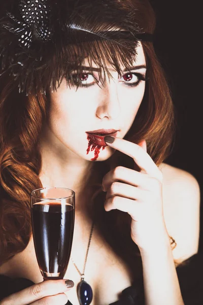 Roodharige vampier vrouw met glas van bloed. — Stockfoto
