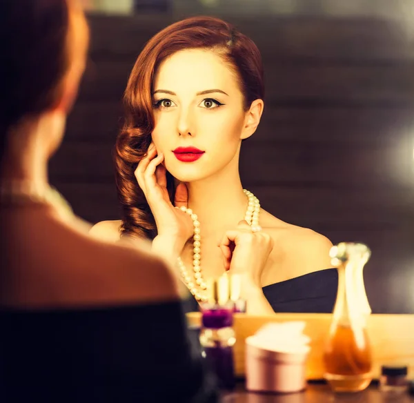 Retrato de una mujer hermosa como la aplicación de maquillaje cerca de un espejo — Foto de Stock