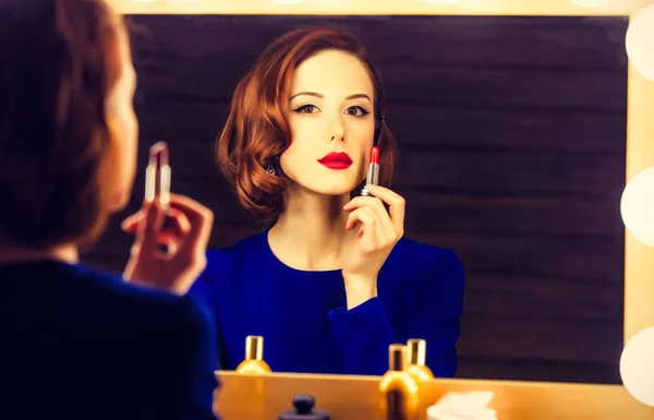 Retrato de una mujer hermosa como la aplicación de maquillaje cerca de un espejo — Foto de Stock