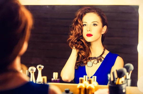 Retrato de uma mulher bonita como aplicação de maquiagem perto de um espelho — Fotografia de Stock