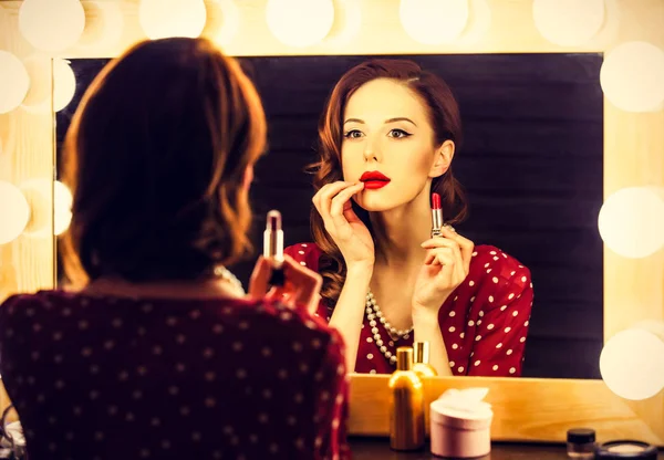 Retrato de una mujer hermosa como la aplicación de maquillaje cerca de un espejo — Foto de Stock