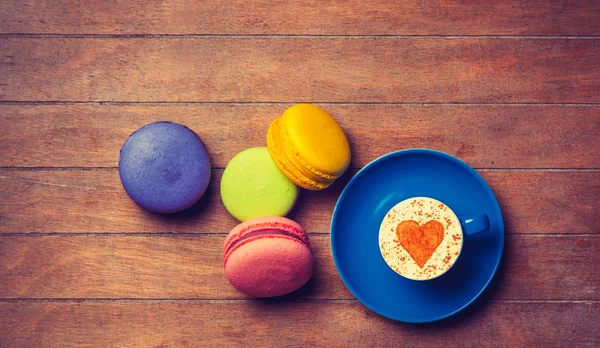 Coupe et macarons sur fond bois — Photo