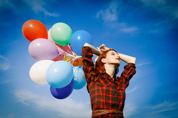 Chica en vestido a cuadros con globos multicolores —  Fotos de Stock