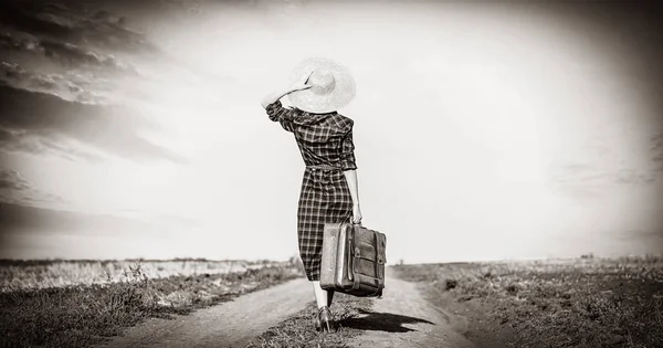 Krásná dívka v kostkované šaty s taškou na venkově. — Stock fotografie