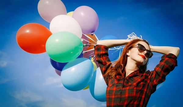 Chica en vestido a cuadros con globos multicolores —  Fotos de Stock