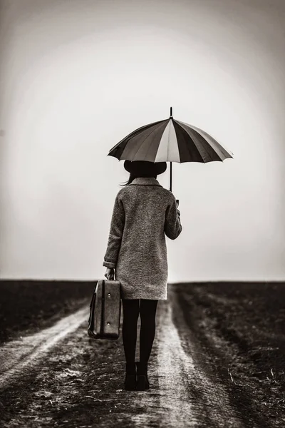 Portrait of a young woman with umbrella and suitcase — Stock Photo, Image