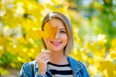 Mavi kot pantolon giysili genç güzel sarışın kızı var dinlenme parkta sonbahar sezonu zamanında.