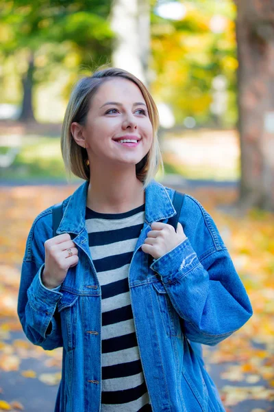 年轻美丽的金发女孩在蓝色牛仔裤衣服有休息在公园在秋季季节时间 — 图库照片