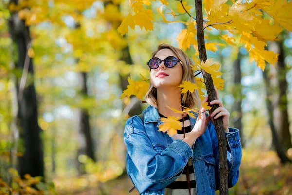 年轻美丽的金发女孩在蓝色牛仔裤衣服有休息在公园在秋季季节时间 — 图库照片