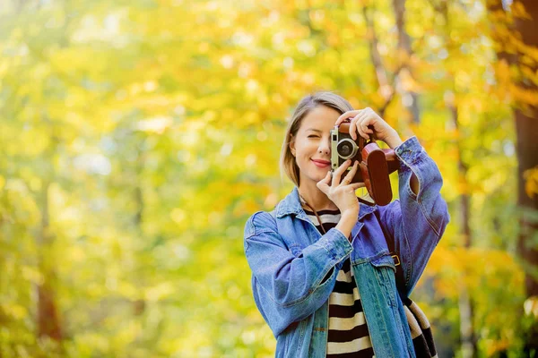 年轻美丽的金发女孩与复古相机有休息在公园在秋季季节时间 — 图库照片