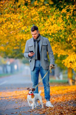 Sonbahar sezonu sokak yürüyen köpek ile genç adam. 