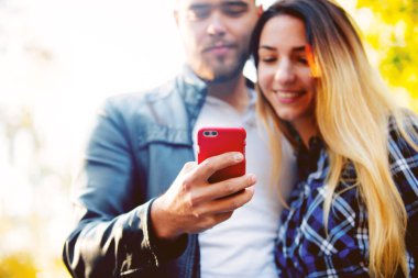 Cep telefonunuzun ve arka planda sarı ağaçları ile bir parkta Genç beyaz çift. Sonbahar sezonu zaman