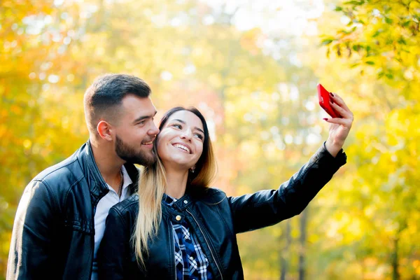 小さな白いカップルは携帯電話の背景に黄色の木がある公園で Selfie を作る 秋シーズンの時間 — ストック写真