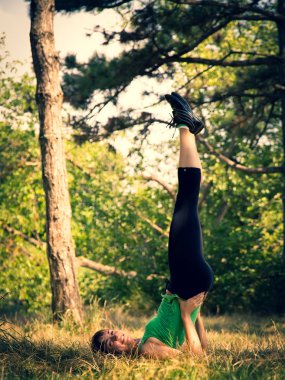 Genç güzel kız bir parkta fiziksel egzersizleri yapıyor.