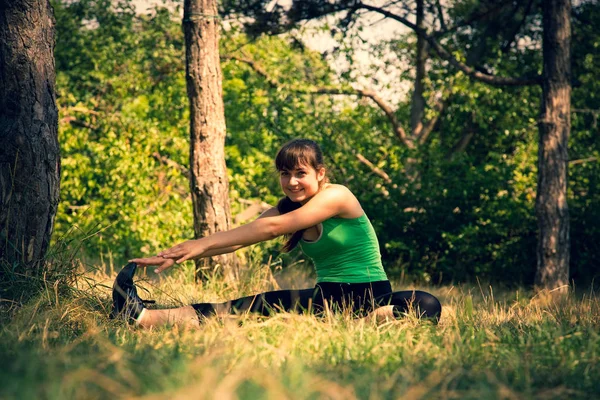 Young beautiful girl doing physical exercises in a park. — Stock Photo, Image