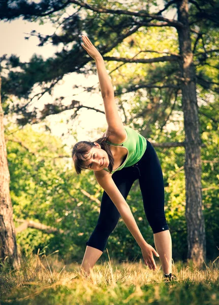 Young beautiful girl doing physical exercises in a park. — Stock Photo, Image