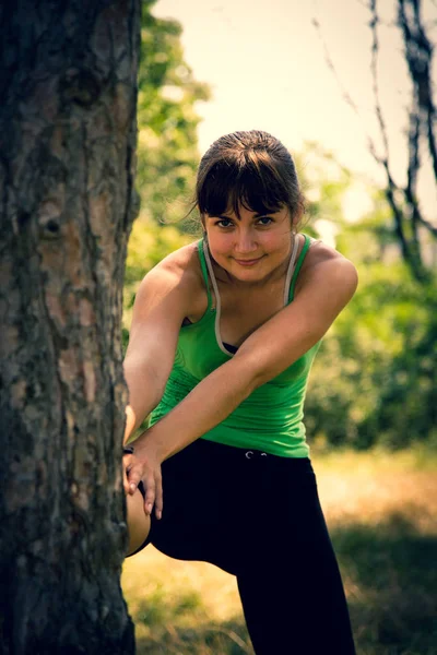 Jovem menina bonita fazendo exercícios físicos em um parque . — Fotografia de Stock
