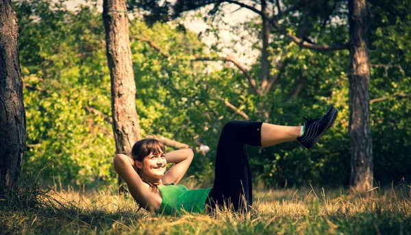 Jovem menina bonita fazendo exercícios físicos em um parque . — Fotografia de Stock