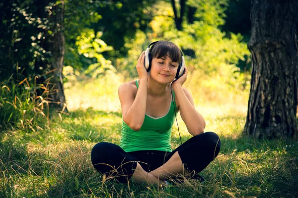 Ung vacker flicka Lyssna på musik i en park — Stockfoto