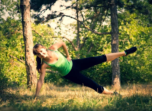 Młoda piękna dziewczyna robi ćwiczenia fizyczne w parku. — Zdjęcie stockowe