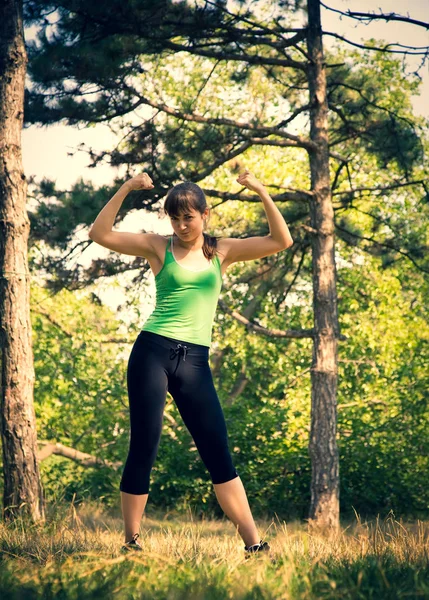 Jovem menina bonita fazendo exercícios físicos em um parque . — Fotografia de Stock