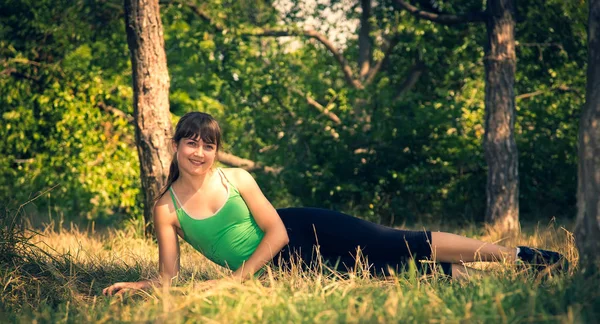 Jeune belle fille faisant des exercices physiques dans un parc . — Photo