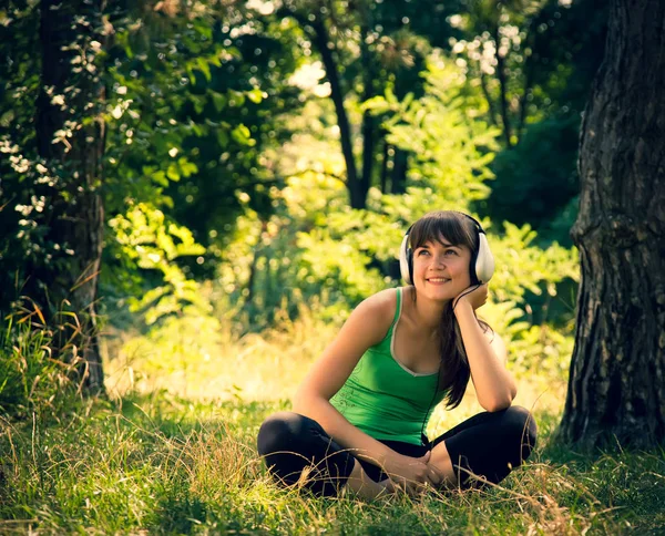 Junges schönes Mädchen hört Musik in einem Park — Stockfoto