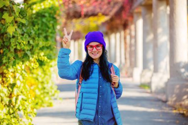 Mavi ceketli genç kız portresi, kırmızı gözlük poz sırt çantası ile sezon sokak düşmek.. 