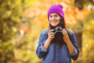 Mor şapkalı Sonbahar Park profesyonel kamera ile fotoğraf yapma genç kadın