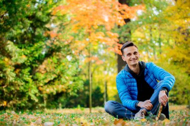 Park zeminde oturan mavi ceketli adamı portresi. Sezon zaman düşmek 