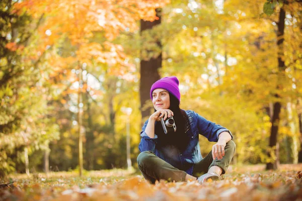 紫色帽子的年轻妇女制作照片与专业相机在秋季公园 — 图库照片